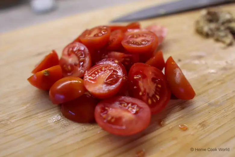Sliced cherry tomatoes on wooden cutting board