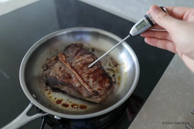 Checking the internal temperature of a steak in the pan.